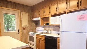 A kitchen with wooden cabinets, a white refrigerator, a stove, an oven, and a dishwasher. - Dewitt -Cozy cabin in the woods- perfect for a small family and a dog near SML State Park (Huddleston)