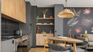 Eine moderne Küche mit integrierter Waschmaschine und Trockner, Holzschränken und einem Essbereich mit rundem Tisch und Stühlen.