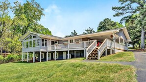 A large, two-story house with a covered porch and a staircase leading to the upper level. - Flip Flop Hideaway- Sandy beach for kids huge yard for dogs and fire pit for smores! (Huddleston)