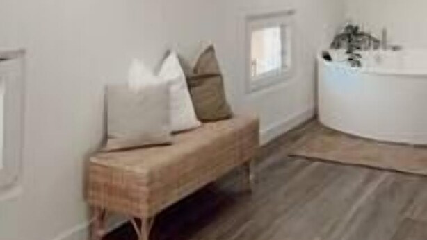 Ein Zimmer mit Dachfenstern, einer Bank, einem kleinen Tisch und einer weißen Badewanne.