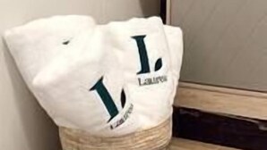 A corner of a room with a woven basket containing a white bag with a logo.
