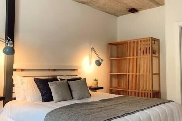 A bedroom with a bed, bedside lamps, a wooden bookshelf, and a headboard. - Liébana Valley Apartment (Oreña)