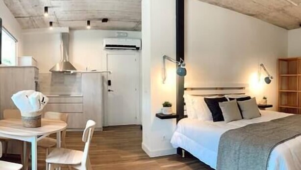 Une chambre d’hôtel moderne équipée d’un lit, de tables de chevet et d’un bureau avec des chaises.