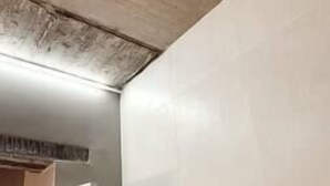 Une pièce avec un mur blanc uni et un plafond apparent laissant voir le béton brut.