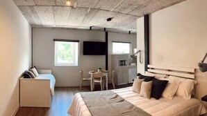 Une chambre comprenant un lit, un bureau, une chaise et un coin cuisine.