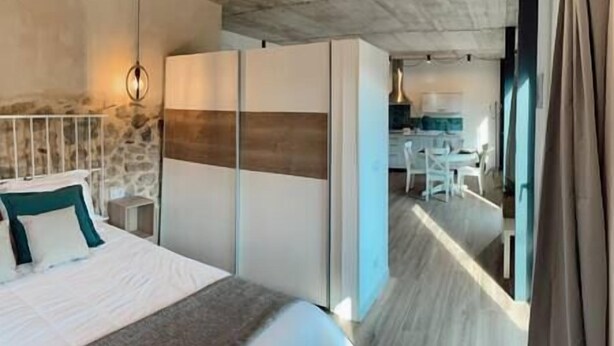 Un dormitorio con cama, armario y zona de escritorio con sillas.