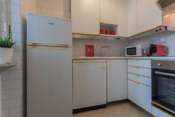 Eine Küche mit weißen Schränken, einer Mikrowelle, einem Toaster und einem Kühlschrank.