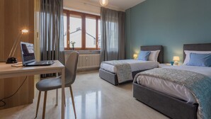 A hotel room with a desk, two beds, a chair, and a window with curtains. - Casa Antonelli by Wonderful Italy (Turin)