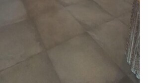 Una habitación con puerta corredera de madera, un espejo grande con marco decorativo y suelo de hormigón.