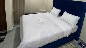 Una habitación de hotel con cama, mesita de noche, lámpara y ventilador de techo.