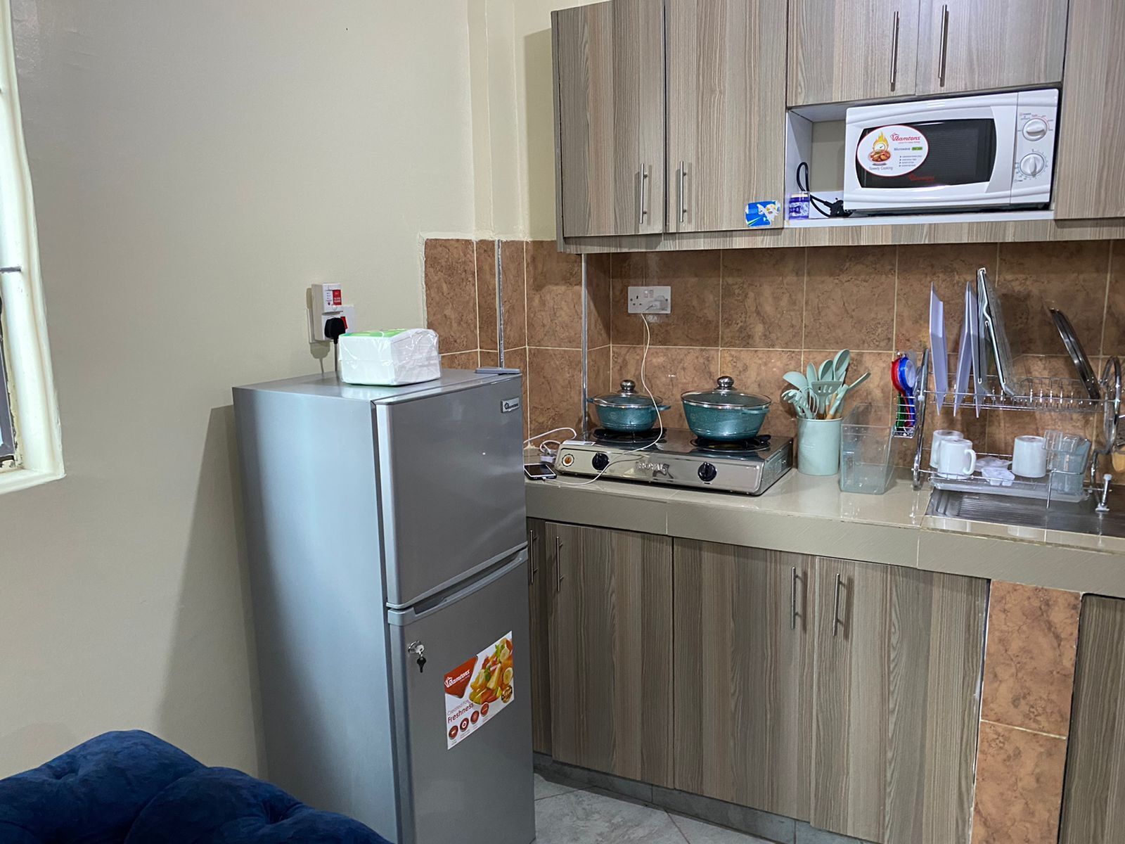 A compact kitchen with a refrigerator, stove, microwave, and wooden cabinets.