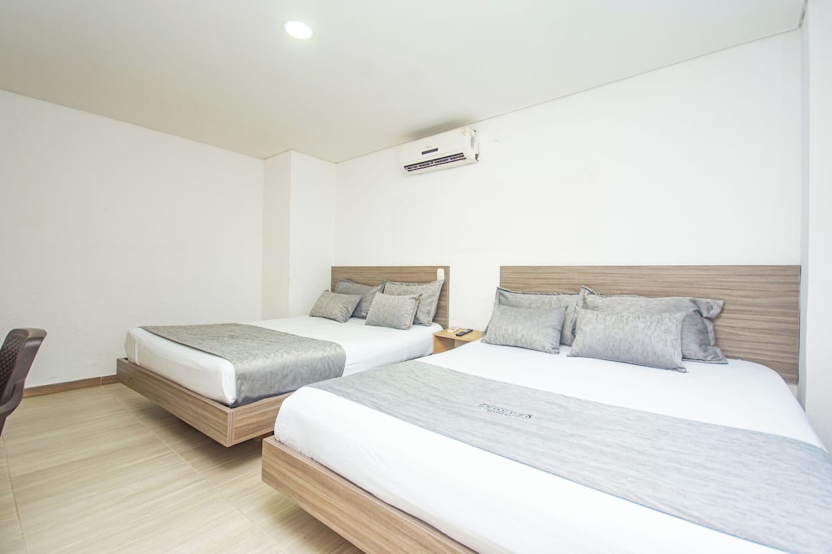 A hotel room with two beds, a desk, and a chair.