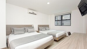 A modern hotel room with two single beds, a wooden floor, a large window with a city view, and a flat-screen TV mounted on the wall. - Novus Laureles (Medellín)