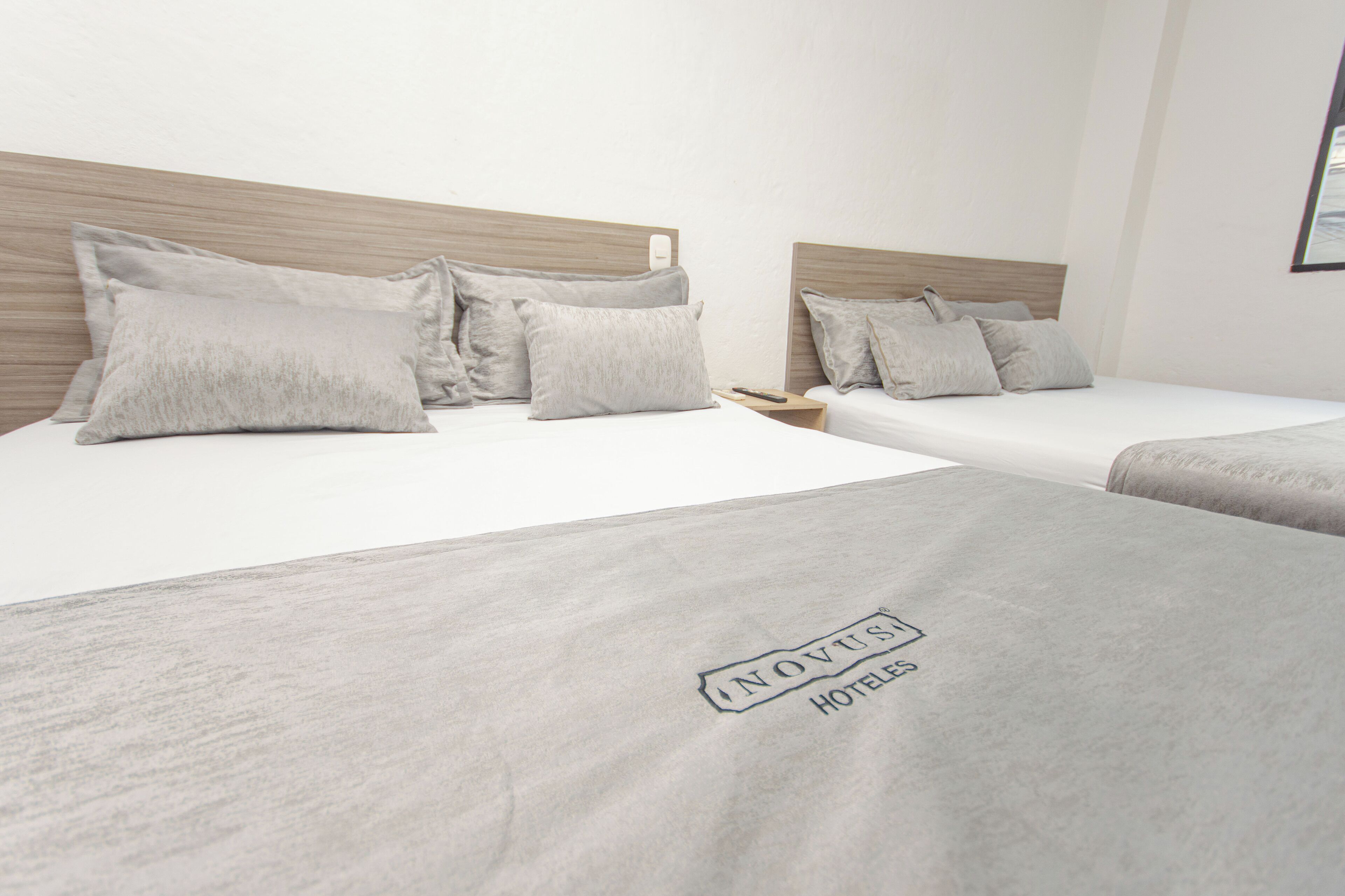 A hotel room with two beds, each with a wooden headboard, and a neutral color scheme.