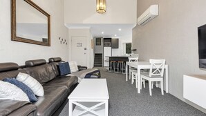 A modern apartment with a living room, dining area, kitchenette, and a staircase leading to an upper floor. - Parkwood 5 - 2BR Split Level l Spa Bath l BBQ l Central Location l WiFi (Jindabyne)