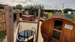 A wooden sauna and cold plunge area with a wooden bench and a hot tub.