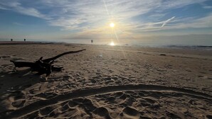 Ein Strand mit Fußabdrücken und einer Holzkonstruktion.