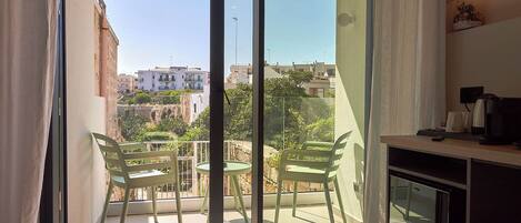 A balcony with two chairs and a table, overlooking a residential area with buildings and greenery.
