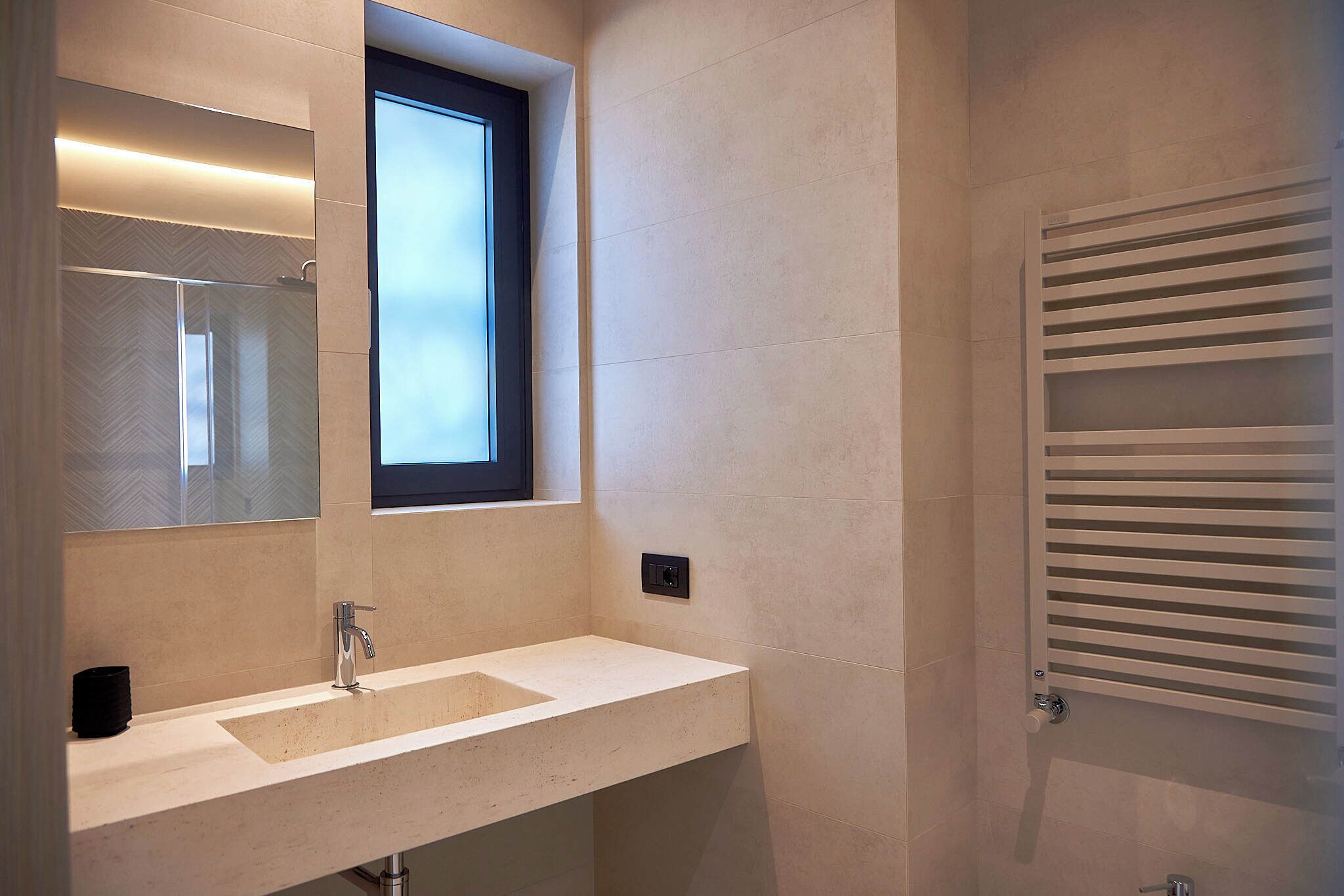 Une salle de bain moderne avec un grand miroir, une fenêtre et un porte-serviettes.