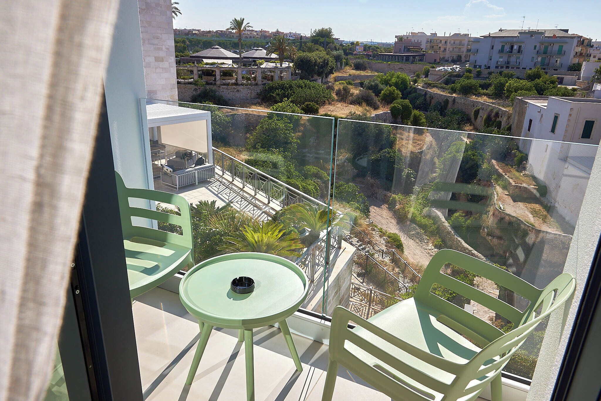 Ein Balkon mit Glasgeländer, einem runden Tisch und zwei Stühlen.