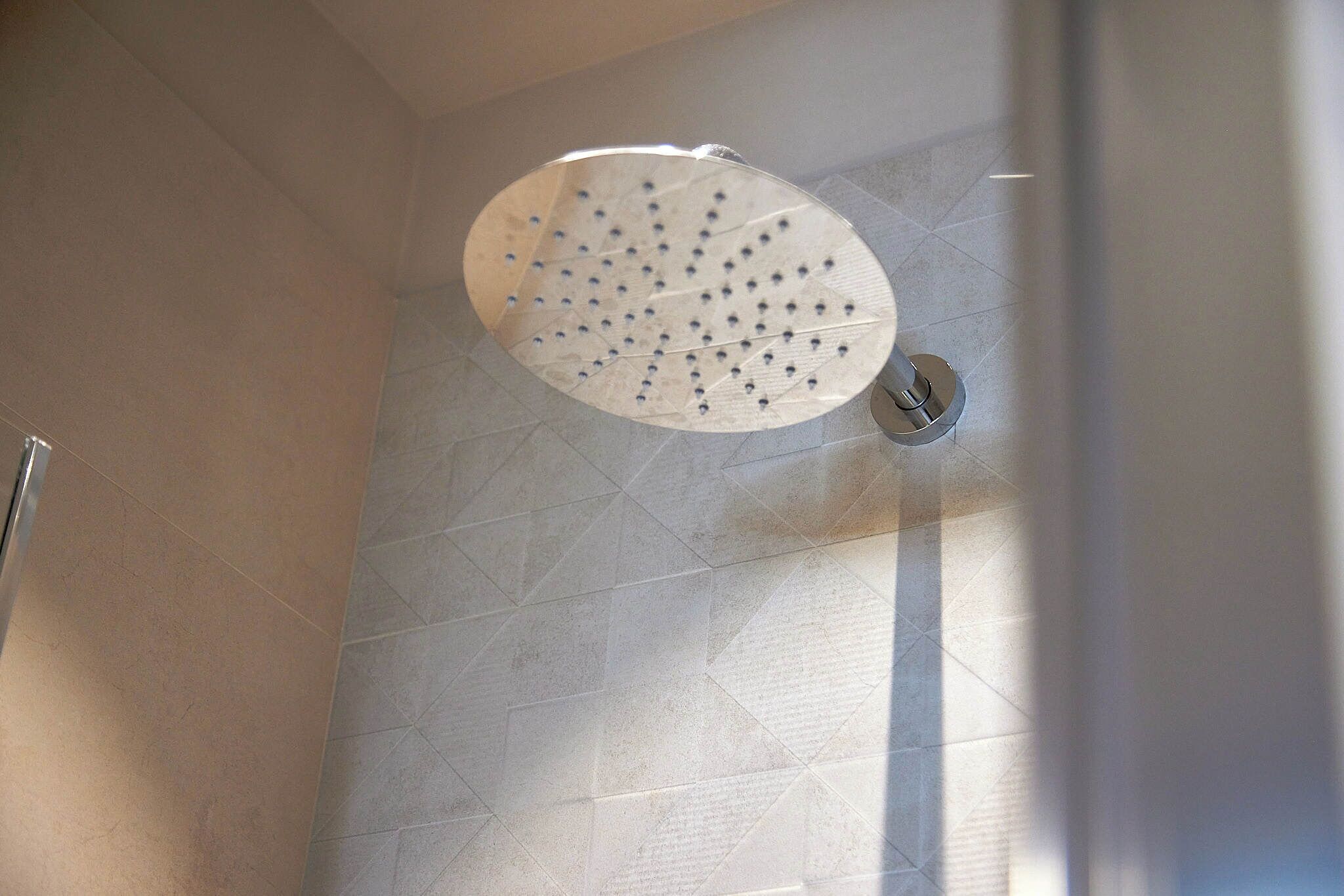 Un pommeau de douche doté de plusieurs jets dans une salle de bain dont les murs sont recouverts de carreaux.