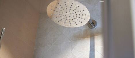 Un pommeau de douche doté de plusieurs jets dans une salle de bain dont les murs sont recouverts de carreaux.