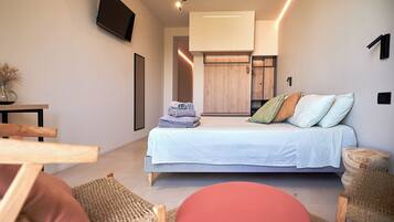 A modern bedroom with a bed, a TV mounted on the wall, and a small table with a vase.