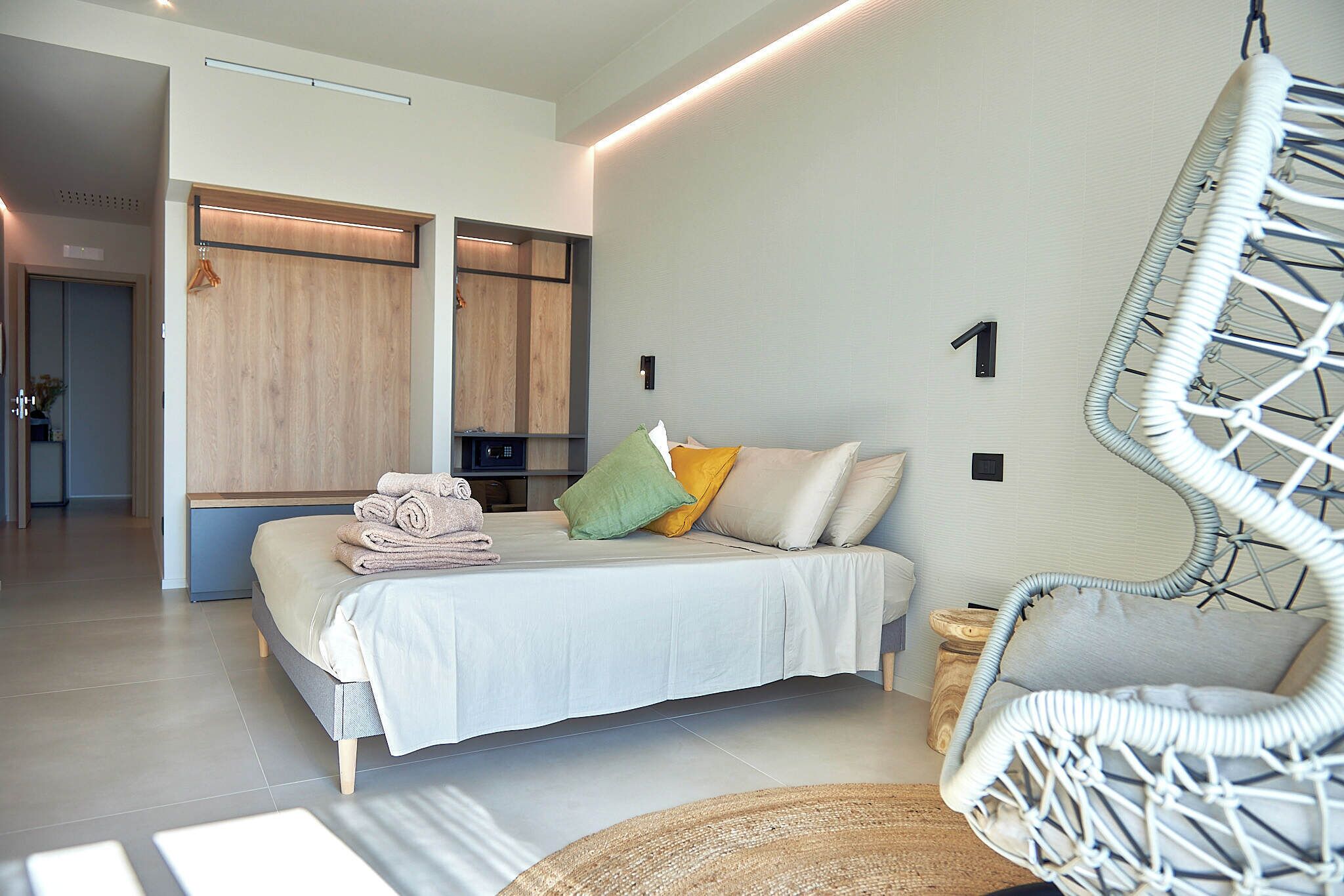 Ein modernes Schlafzimmer mit Bett, Hängesessel und Kleiderschrank.