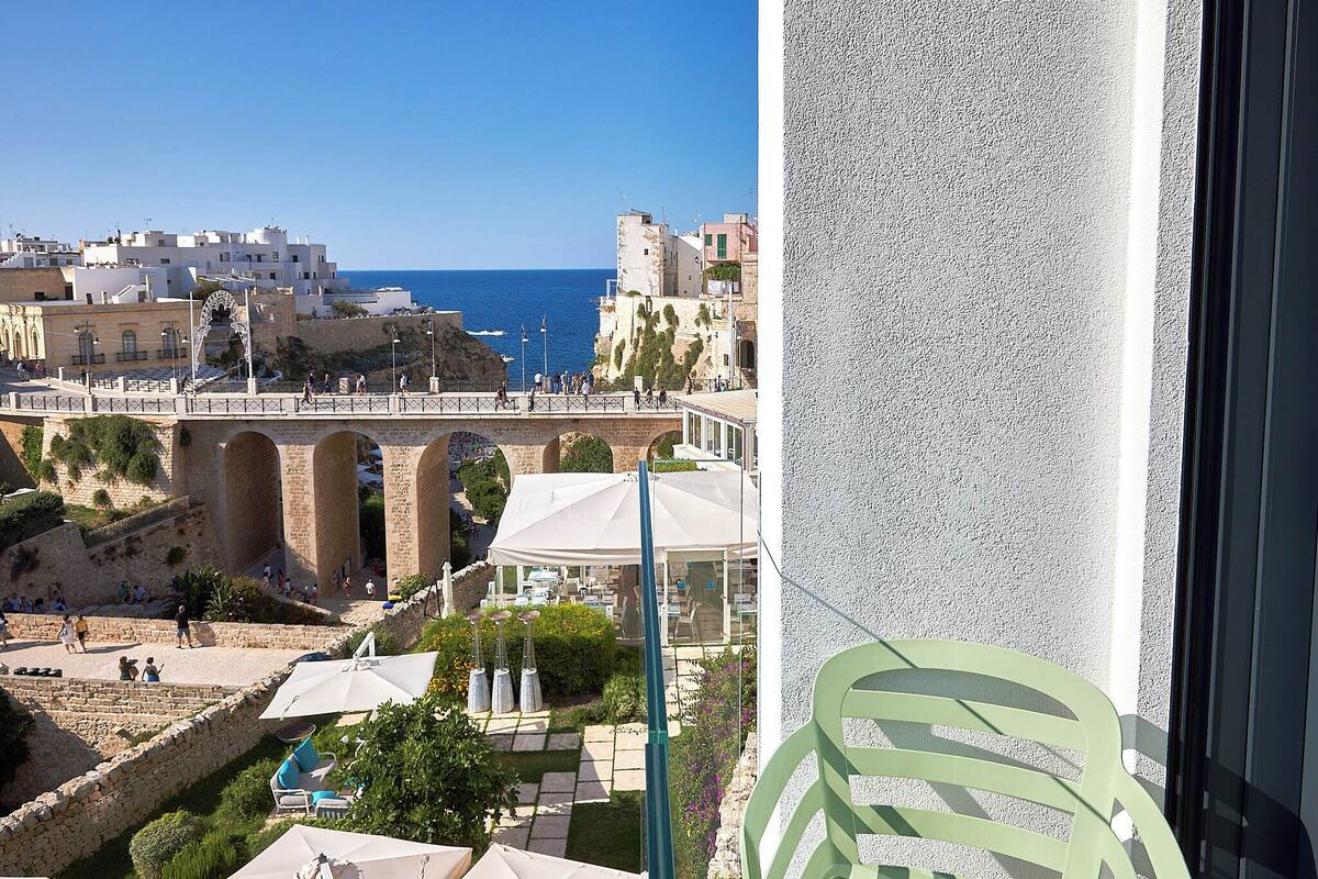A coastal view with a stone bridge, outdoor seating, and a pool area.