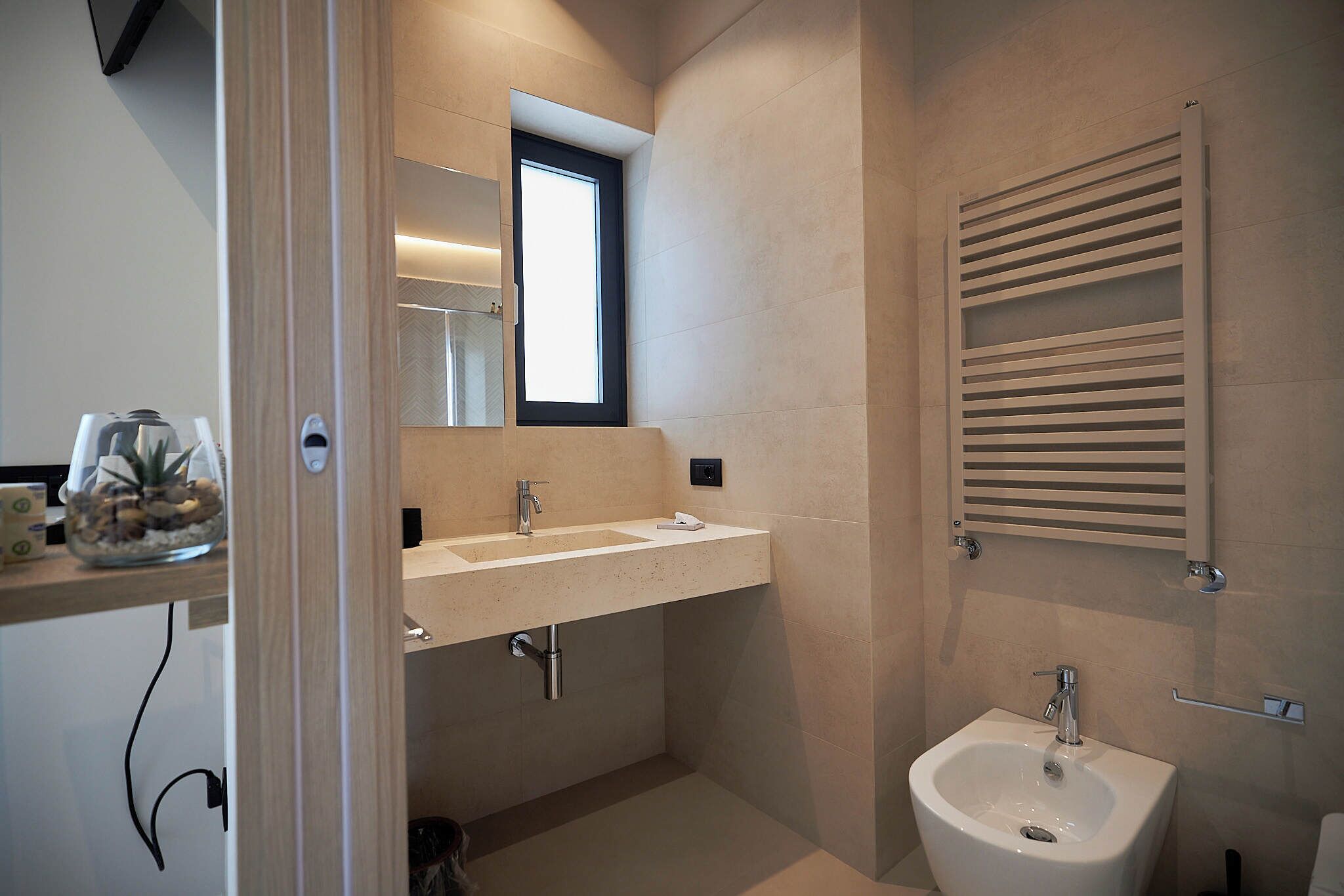 A modern bathroom with a double sink, a bidet, and a towel rack.