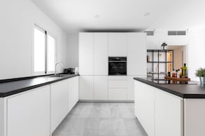 A modern kitchen with white cabinetry, a black countertop, and a built-in oven. - Jardines Puerto Banús – Elegance and Comfort in Marbella’s Heart (Marbella)