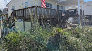 Ein zweistöckiges Haus mit einer Holzterrasse und einer amerikanischen Flagge.