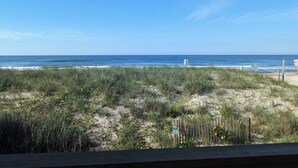 Blick auf einen Strand mit Holzzaun und Schild für einen Parkplatz.