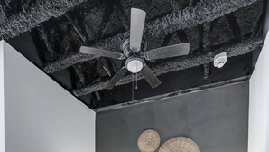 Une chambre à coucher avec un lit, un ventilateur de plafond et des œuvres d’art décoratives au mur.