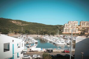 A marina with boats docked, a clear sky, and a hilly landscape in the background.