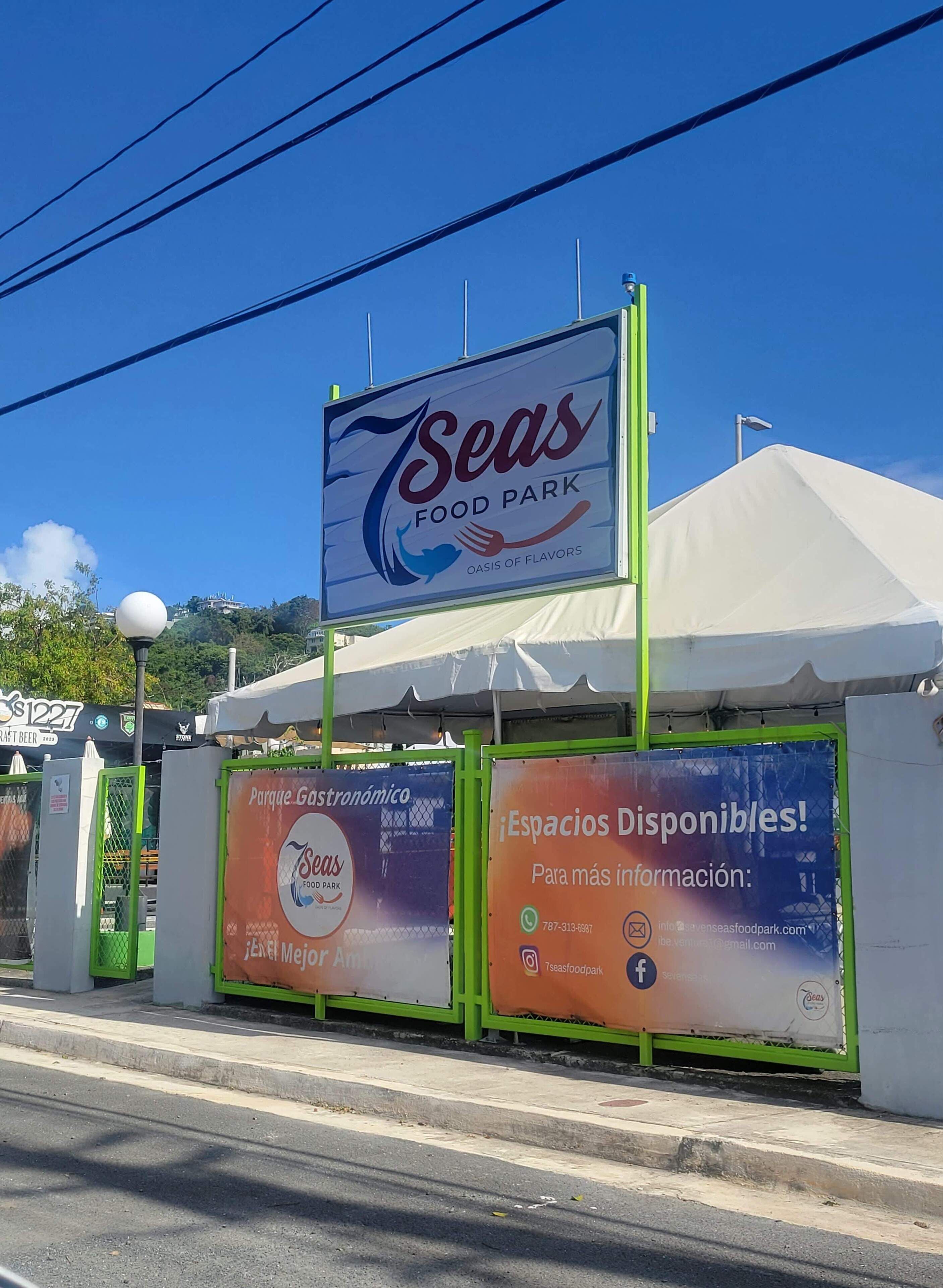 Een bord voor Seas Food Park met een tentstructuur en advertenties voor Parque Gastronómico en beschikbare ruimtes.