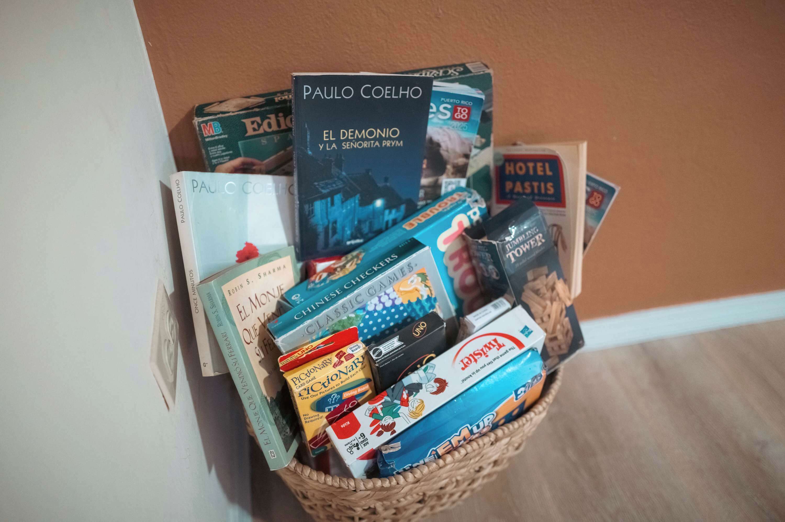 A basket filled with various items including books, board games, and a Hotel Pastis card.