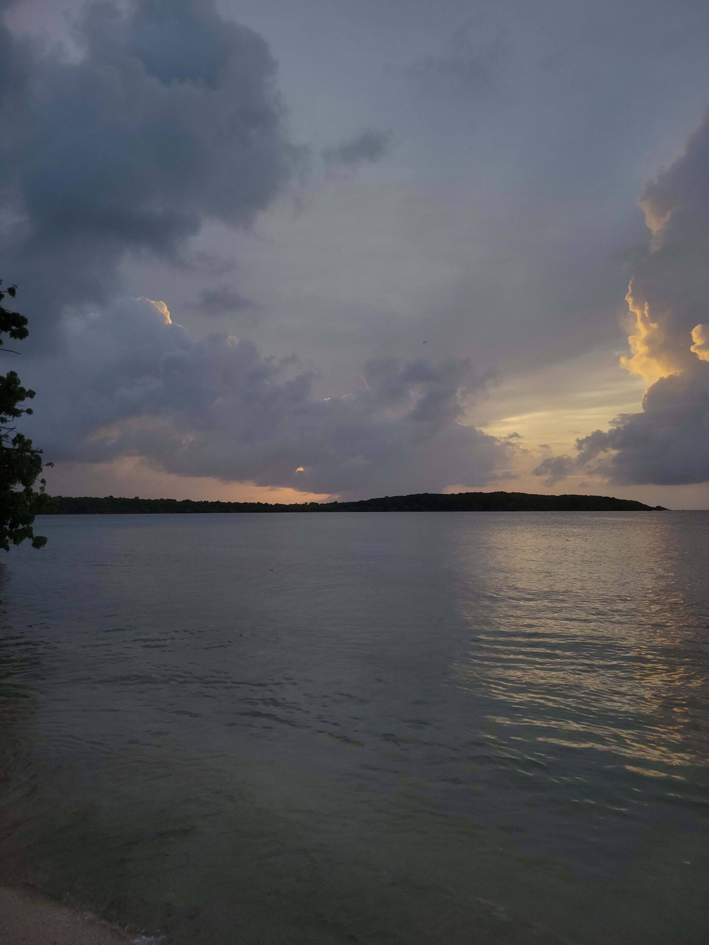 A calm body of water with a distant shoreline and overcast sky.