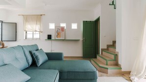 A living room with a teal sofa, a green door, and a staircase with green steps.