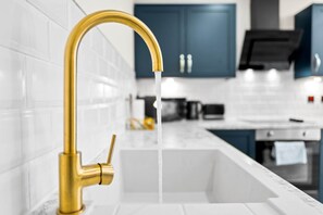 A kitchen with a gold faucet and white tiles. - Luxury 2 Bed Apartment - Smart TV - WIFI -  Jewellery Quarter (Birmingham)