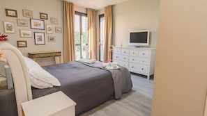 A bedroom with a bed, bedside table, dresser, TV, and framed pictures on the wall. - Lugana Lovers - Two Bedroom Apartment, Sleeps 6 (Sirmione)
