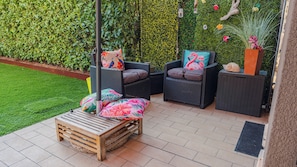 An outdoor seating area with wicker furniture, a wooden bench, and a decorative wall. - Lugana Lovers - Two Bedroom Apartment, Sleeps 6 (Sirmione)