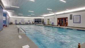 Une grande piscine intérieure dotée de plusieurs couloirs de nage, d’un poste de surveillance pour les sauveteurs et d’un vestiaire.