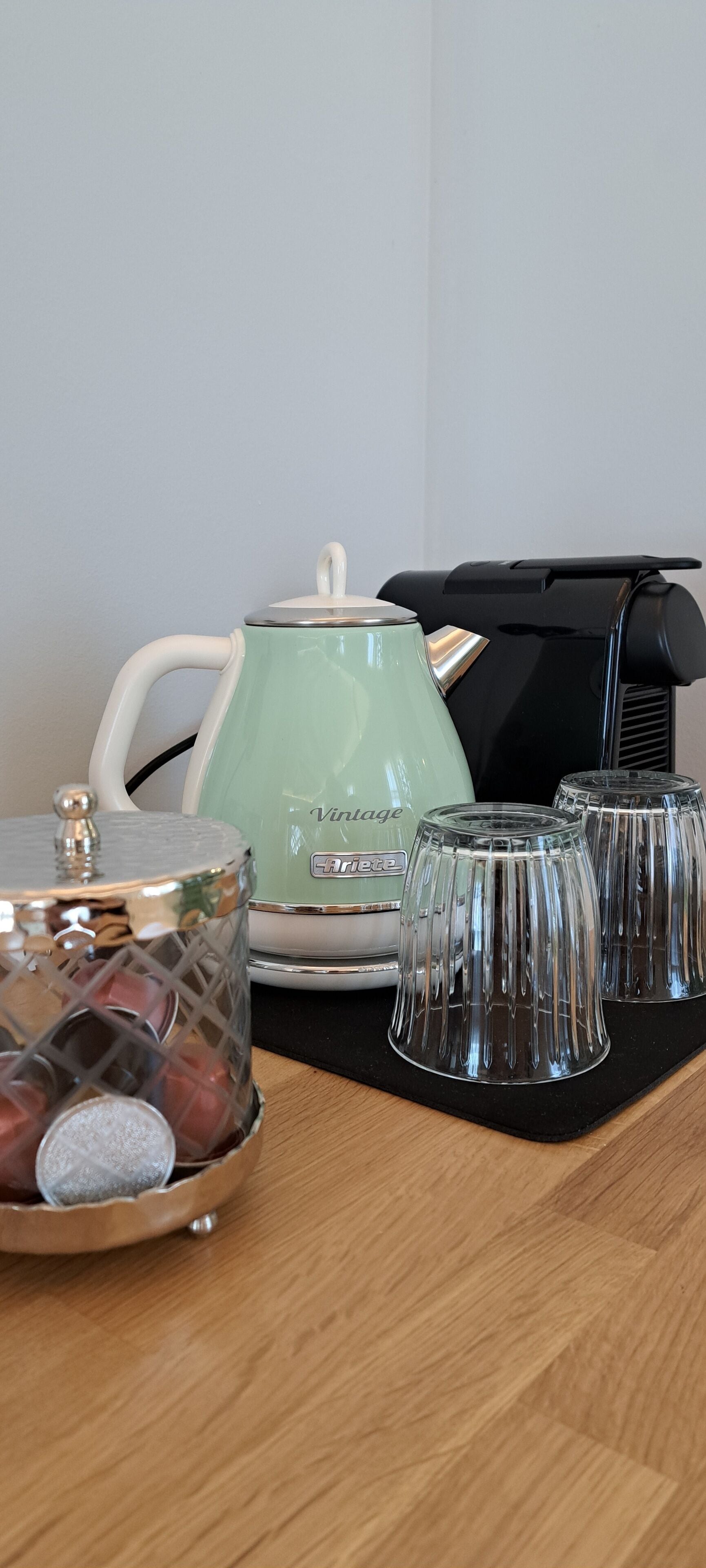 A kitchen counter with a green kettle, a coffee maker, and a glass container with a lid.