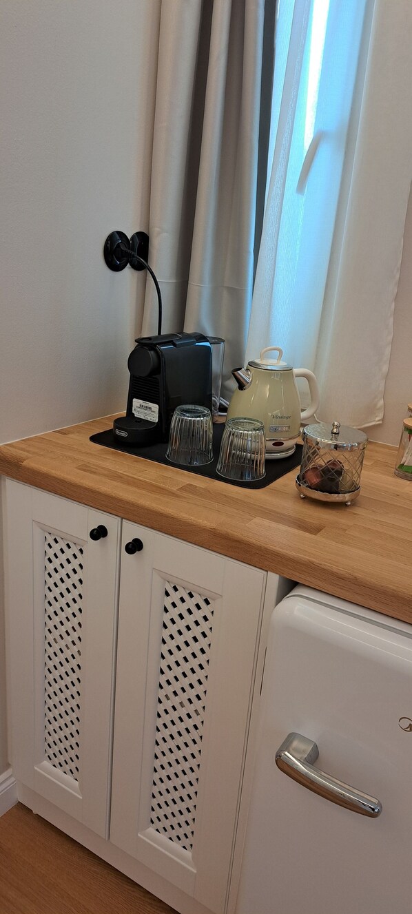 A kitchenette with a coffee maker, kettle, and glassware on a wooden countertop. - VERANI SUITES (Lefkada)