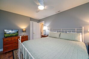 Un dormitorio con cama, cómoda, televisor, ventilador de techo y puerta.