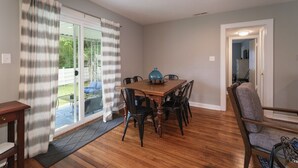 A dining area with a wooden table and chairs, a blue decorative item, and a sliding glass door leading to a patio. - Johnson Street Cottage in Downtown Brevard (Brevard)