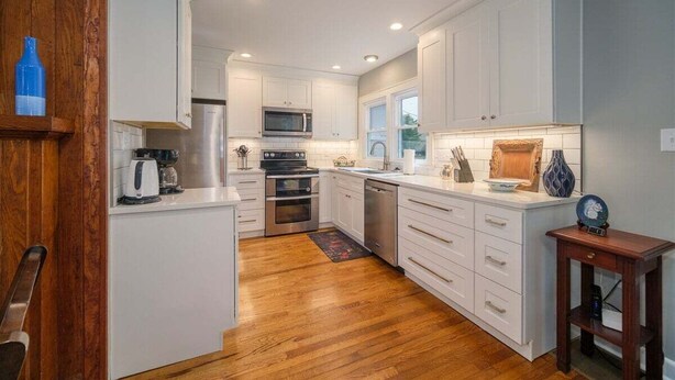 A modern kitchen with white cabinetry, stainless steel appliances, and a wooden floor. - Johnson Street Cottage in Downtown Brevard (Brevard)
