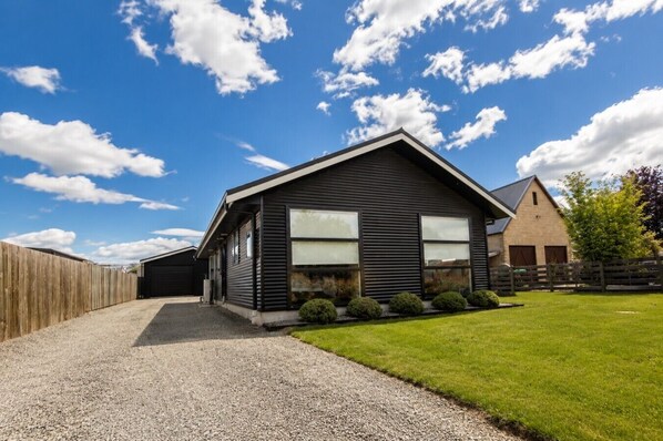 A modern two-story house with a gravel driveway and a fenced yard.