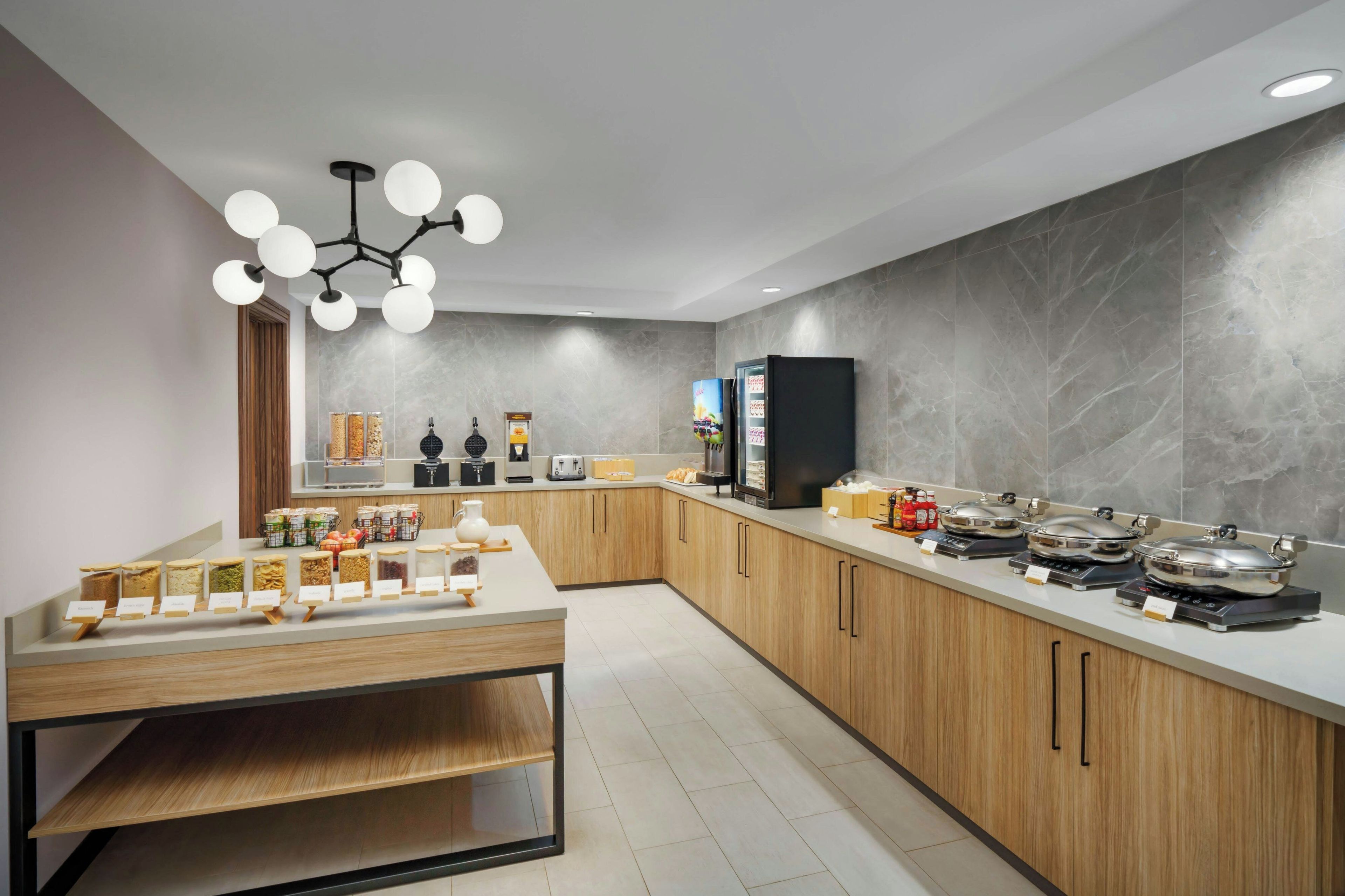 A modern kitchen with a central island, a coffee machine, and a refrigerator.